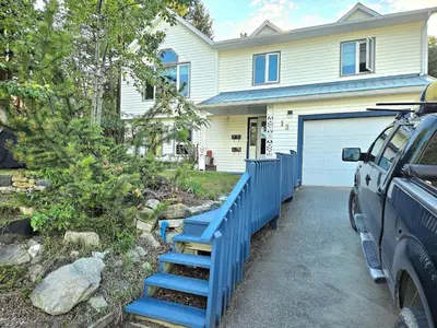 a house with a blue fence and a car parked in front at The Hilltop in Whitehorse