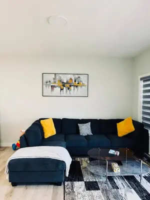 a living room with a blue couch and yellow pillows at Cozy house with 4 Bedrooms 3 Full bath and 1 half bath in Calgary