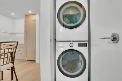 a washer and dryer in a room with a chair at New condo Great amenities Near Skytrain in Coquitlam