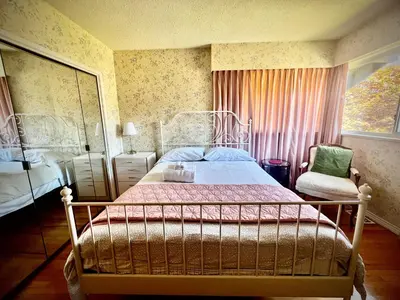 a bedroom with a bed and a chair and a window at Luxury Space close to UBC in Vancouver