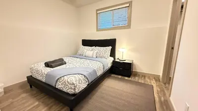 a bedroom with a bed with a black headboard and a window at Red Deer Stay- 2BR Private Suite in Red Deer