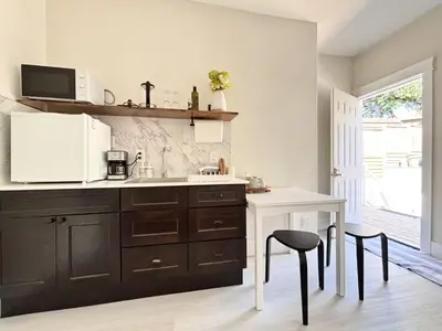 a kitchen with a sink and a table and two stools at Vancouver Mini Suite in Vancouver