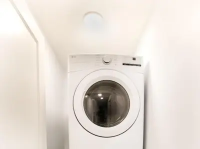 a white washing machine in a white room at Olympia Lodge 2 room Apartment in Calgary