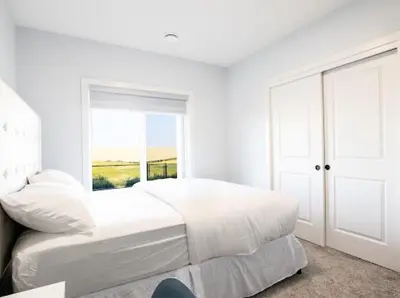 a white bedroom with a bed and a window at Olympia Lodge 2 room Apartment in Calgary