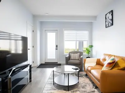 a living room with a couch and a table at Olympia Lodge 2 room Apartment in Calgary