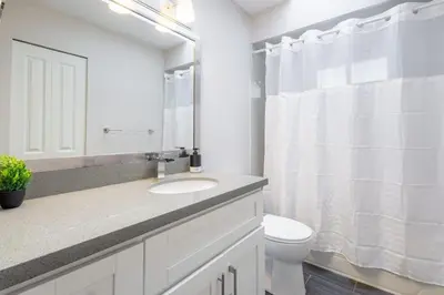 a white bathroom with a sink and a toilet at Soothing Minimalist Escape - Suite with Balcony & Fireplace in Vancouver