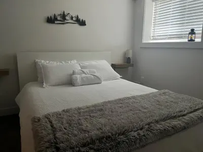 a bedroom with a white bed with a blanket at Cedar & Sage Suite the Cozy Retreat with Full Kitchen in Victoria