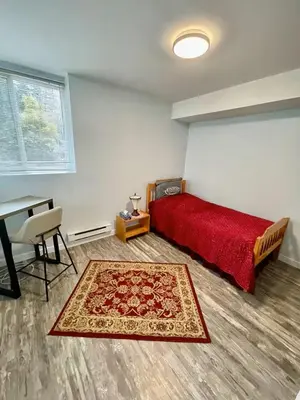 a bedroom with a red bed and a table and a rug at Holiday Home in Coquitlam