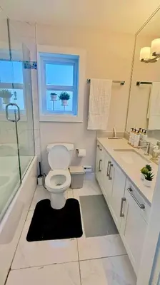 a white bathroom with a toilet and a window at The Cozy Quad In the Heart of Vancouver in Vancouver