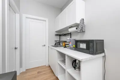 a kitchen with white cabinets and a counter with a microwave at Cozy Langford suite in Langford