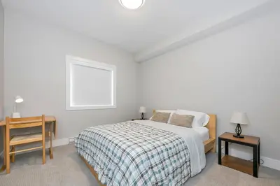 a white bedroom with a bed and a table at Cozy Langford suite in Langford