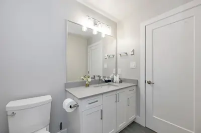 a white bathroom with a sink and a mirror at Cozy Langford suite in Langford