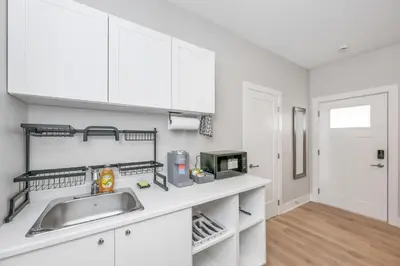 a kitchen with white cabinets and a sink at Cozy Langford suite in Langford