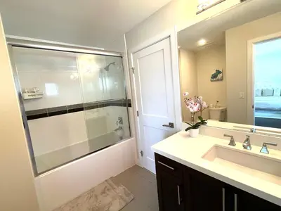 a bathroom with a glass shower and a sink at European-American Style Suite in Coquitlam