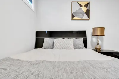 a bedroom with a white bed with a black headboard at Private, Stylish and Peaceful 2BR Guest Suite in Calgary