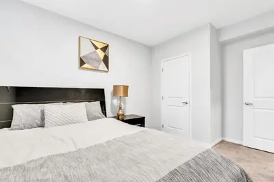 a bedroom with a bed and a lamp on a table at Private, Stylish and Peaceful 2BR Guest Suite in Calgary