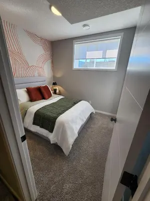 a small bedroom with a bed and a window at Brand New Modern 2 Bedroom Basement Suite in Calgary
