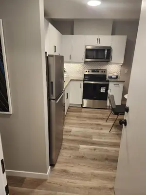 a kitchen with white cabinets and a stainless steel refrigerator at Brand New Modern 2 Bedroom Basement Suite in Calgary