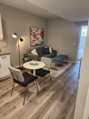 a living room with a couch and a table and chairs at Brand New Modern 2 Bedroom Basement Suite in Calgary