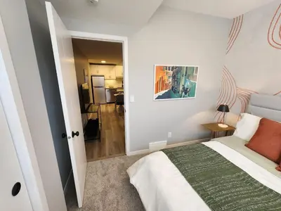 a bedroom with a bed and a door leading to a kitchen at Brand New Modern 2 Bedroom Basement Suite in Calgary