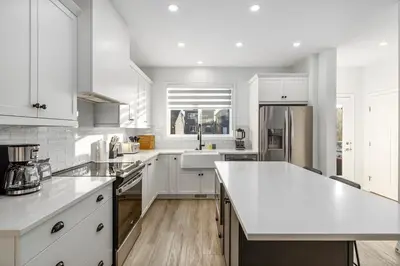 a kitchen with white cabinets and a white counter top at King Bed, AC, Fenced Yard, Family Friendly, 5 min South Health Campus in Calgary