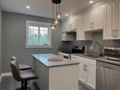 a kitchen with white cabinets and a counter top at Sunshine garden 3 bedrooms2 bathrooms1 living room1 kitchen in Aldergrove
