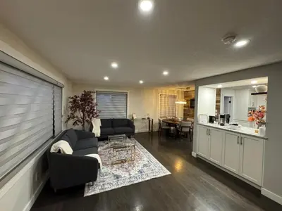 a living room with a couch and a kitchen at Luxurious Air Conditioned Inner City Bungalow in Calgary