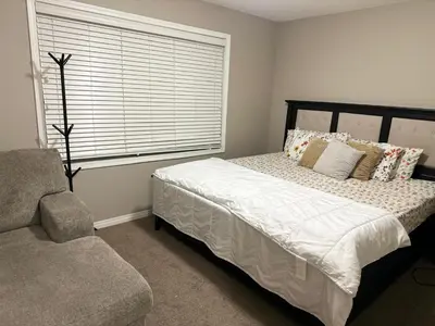 a bedroom with a bed with pillows and a window at Spacious Bedroom-Near Airport YYC in Airdrie
