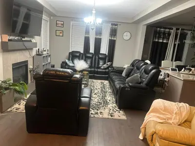 a living room with black leather furniture and a kitchen at Spacious Bedroom-Near Airport YYC in Airdrie
