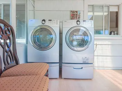 two washing machines and a chair in a kitchen at Cozy Airb&b Suite in South Vancouver in Vancouver
