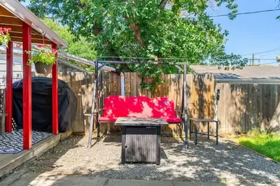 a patio with a red couch and a fence at The Red Steps Away From World's Largest Dinosaur 3BR House in Drumheller