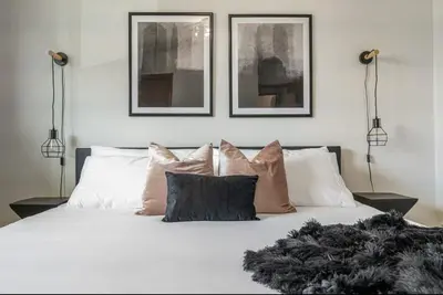 a bedroom with a white bed with three pictures on the wall at The Coal Stone throw away from Red Deer River 2BR House in Drumheller