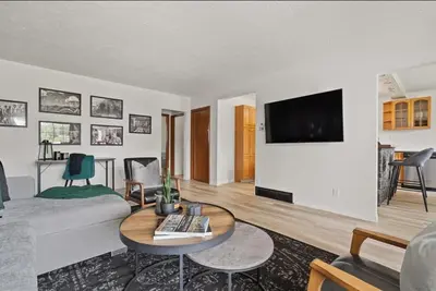 a living room with a couch and a tv on a wall at The Coal Stone throw away from Red Deer River 2BR House in Drumheller