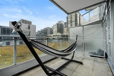 a hammock on a balcony with a view of a city at Luxury Waterfront Suite with City Views and AC in Calgary