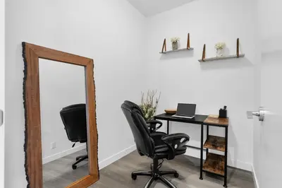 an office with a mirror and a desk with a laptop at Luxury Waterfront Suite with City Views and AC in Calgary