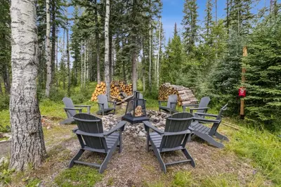 a group of chairs around a fire pit in the woods at Nordegg Timber Estate in Nordegg