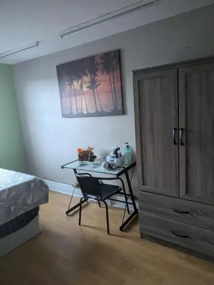 a bedroom with a table and a bed and a cabinet at Tania's guest rooms in Calgary