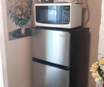 a microwave sitting on top of a refrigerator at Tania's guest rooms in Calgary