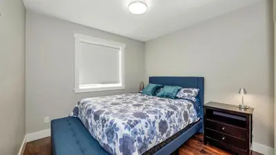 a bedroom with a blue bed and a window at Knockan Hill Rentals - Garden Suite in Victoria