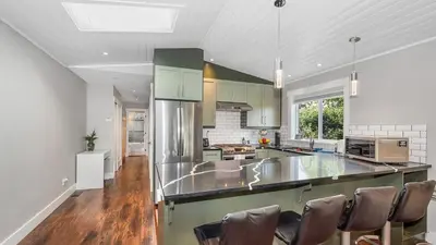 a kitchen with a large island with chairs in it at Knockan Hill Rentals - Garden Suite in Victoria