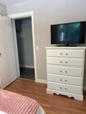 a white dresser with a television on top of it at Golfers getaway home in the trees in Roberts Creek