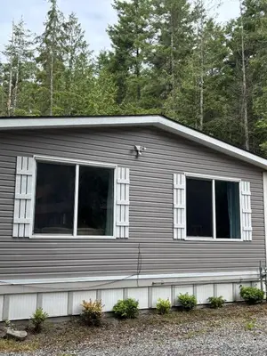 a gray house with two windows on it at Golfers getaway home in the trees in Roberts Creek
