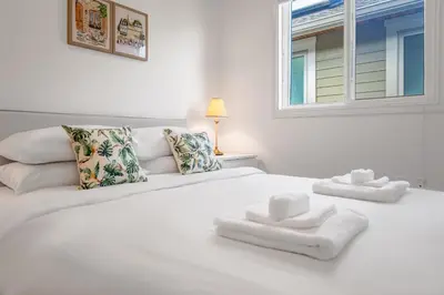 a white bed with white pillows and a window at Central Spacious 3 Br Upstairs in Vancouver