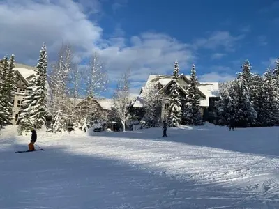 a person on skis in the snow in front of a house at XL Luxury Penthouse Ski-in Ski-out The Aspens in Whistler