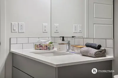 a bathroom counter with a sink and a mirror at Executive Single Detached House with AC King Bed and More in Calgary