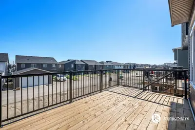 a balcony with a wooden deck with black railing at Executive Single Detached House with AC King Bed and More in Calgary