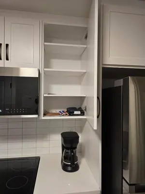 a kitchen with white cabinets and a black stool at Guest Suite in Southwest Calgary in Calgary