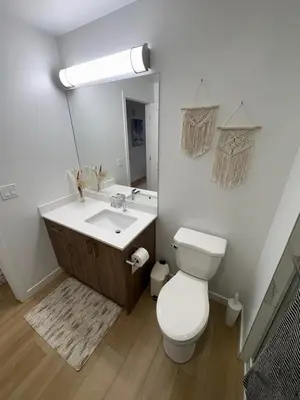 a bathroom with a toilet and a sink and a mirror at Boho Studio Downtown Rogers Views Heated Parking in Edmonton