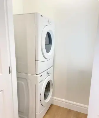 a washer and dryer in a white laundry room at Cozy New Suite 8mins to Downtown in Vancouver