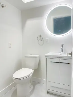 a white bathroom with a toilet and a sink at Cozy New Suite 8mins to Downtown in Vancouver